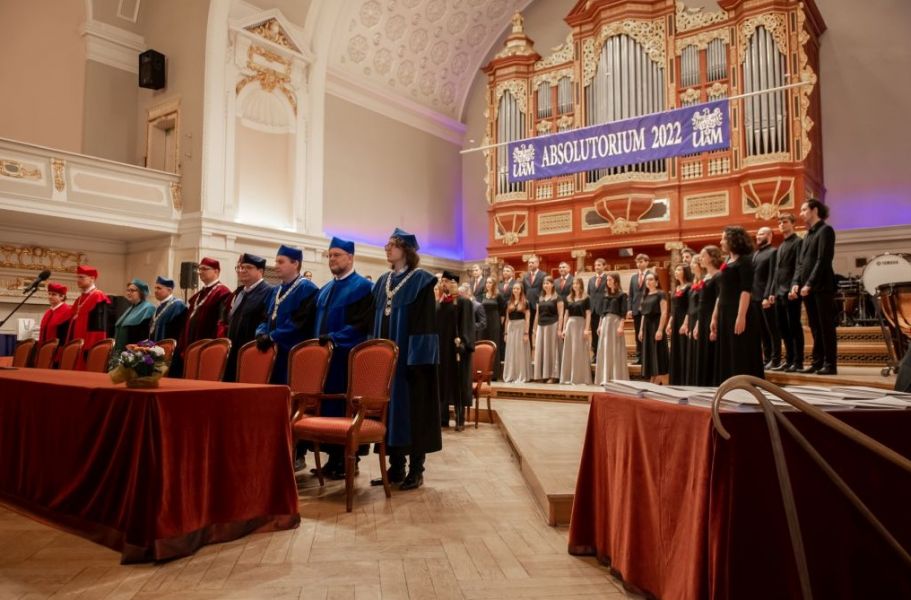 zdjęcie stojących na scenie władz rektorskich i dziekańskich , w tle chór UAM