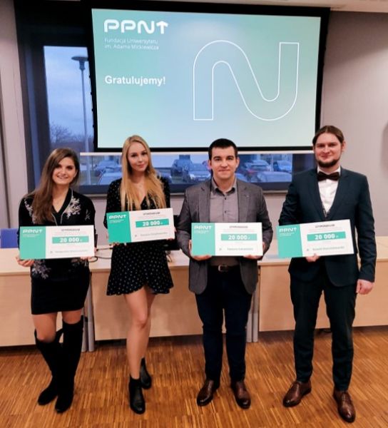 na zdjęciu w sali na tle logo PPNT stoi 4 laureatów stypendiów Fundacji UAM z Wydziału Chemii